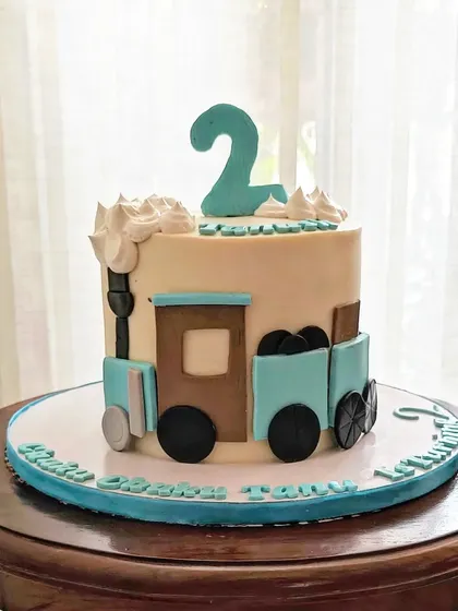 A sweet and simple train-themed cake for a 2nd birthday. The fondant train is carrying a load of "coal" made from crushed Oreo cookies.