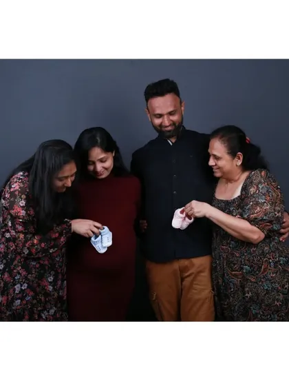 The family guessing the baby's gender with tiny shoes. Using simple props like this can add a playful and heartwarming element to your maternity photoshoot, creating fun memories for everyone involved.