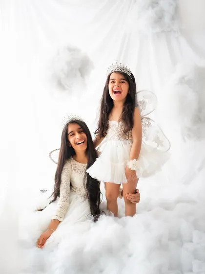 Pure, unfiltered joy. My dreamy clouds setup is a favorite for kids' photoshoots, and these sisters brought all the happy energy. Capturing genuine laughter like this is my absolute favorite part of being a children's photographer.