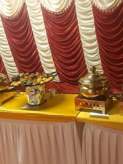 A buffet table with appetizers and main courses set against a festive red and white backdrop, perfect for a wedding or traditional ceremony.