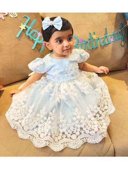A beautiful little client celebrating her birthday in the "Arya" dress. The powder blue color and white lace detailing make it a timeless and elegant choice for a first birthday.