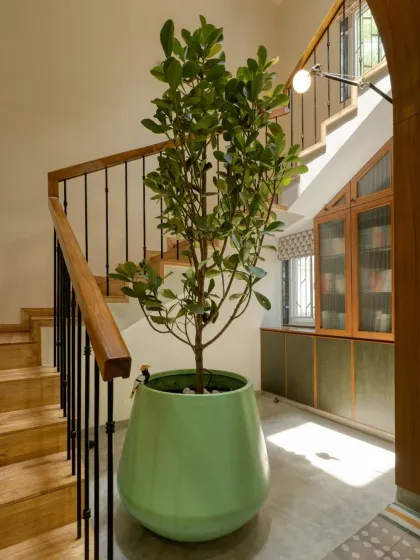 A sunlit stairwell at Villa 17 that we transformed into a quiet retreat. It features a custom-built bookshelf tucked under the stairs and a large planter.