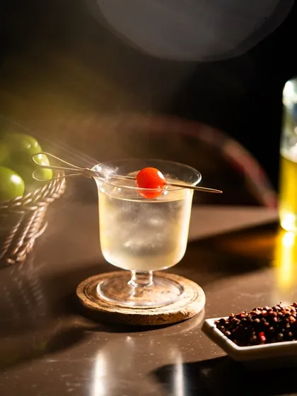 A clear martini-style cocktail with a single cherry. This is a clean, minimalist shot that emphasizes elegance and simplicity.