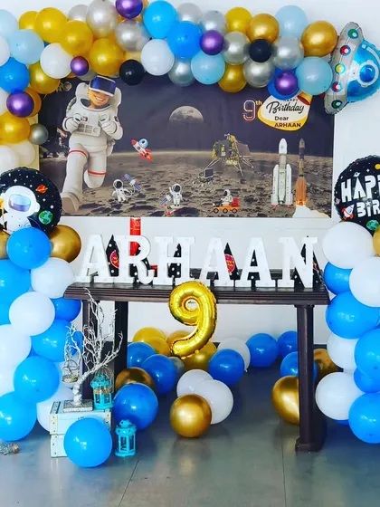 An out-of-this-world space theme for Arhaan's 9th birthday. This home setup includes a galaxy backdrop, a balloon frame in blue, gold, and white, and a custom marquee name display.