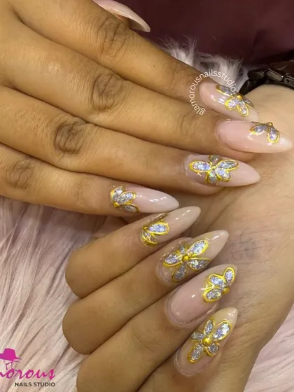 Elegance in 3D. These long, stiletto-shaped nails have a soft nude base, making them the perfect canvas for these stunning 3D butterfly embellishments, crafted with gold and filled with sparkling silver glitter.
