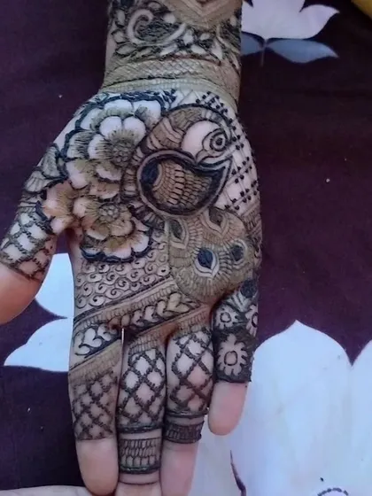 Another example of a peacock design, this time placed on the palm. It's surrounded by floral and geometric patterns, making it a beautiful focal point.