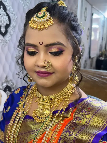 The complete look with a focus on the harmony between the makeup, jewelry, and the orange and blue Nauvari saree.
