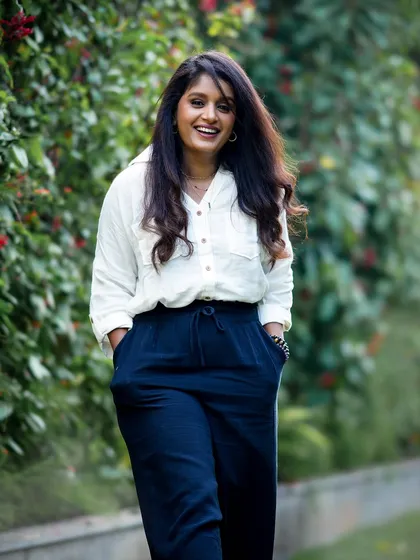 A happy and casual outdoor portrait of a woman walking with her hands in her pockets, exuding confidence.