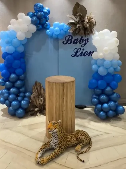 The main backdrop for our "Baby Lion" welcome party. A cute leopard prop, a wooden pedestal, and a blue and white balloon arch created a fun and playful jungle vibe.