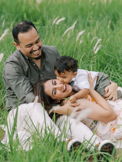 A family enjoying a tender moment in a field of tall grass. The natural setting adds a beautiful, rustic feel to the portrait.