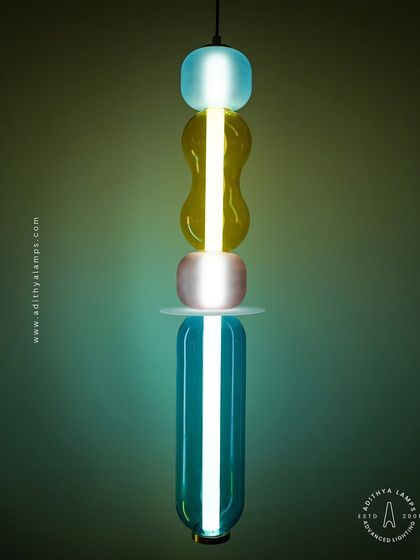 Add a playful pop of color with these kinetic sculpture pendants. Featuring stacked segments of hand-blown glass in teal, amber, and blush, these lights are a fun and artistic addition to any creative space.