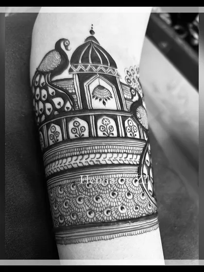 A black and white shot of a detailed armband with a peacock and architectural dome.