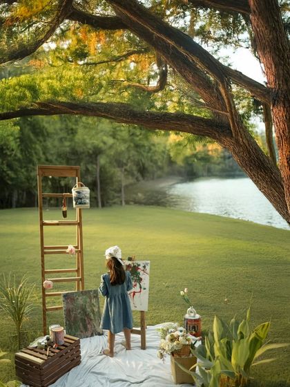 Captured from behind, a little girl is absorbed in her painting, set against a beautiful lakeside backdrop. This shot focuses on the act of creation and the child's complete immersion in her artistic world.