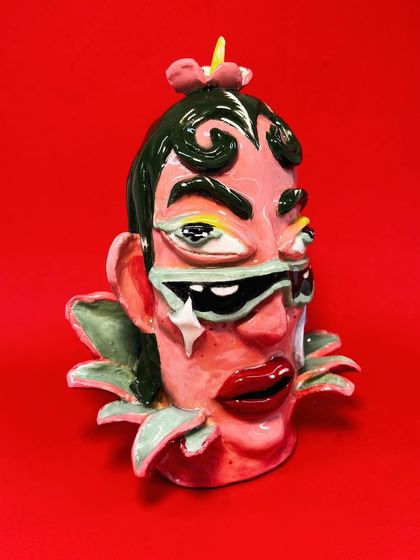 A close-up of one of the finished 'Glazed & Confused' heads against a red background.