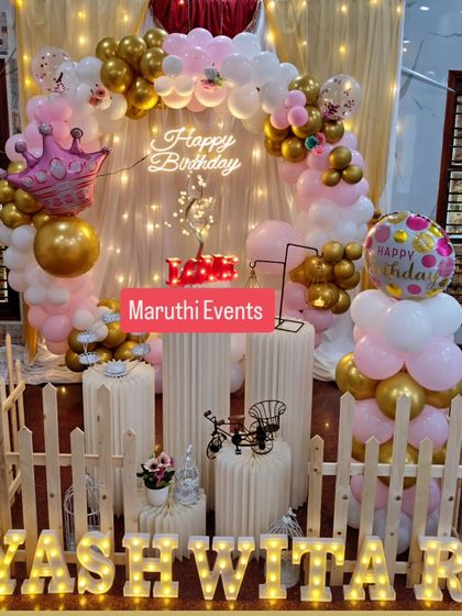 A princess-themed birthday with a touch of rustic charm. The pink, white, and gold balloon arch is paired with a white picket fence and elegant plinths.