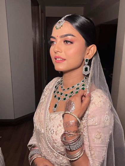 This bride looks absolutely regal with her sleek bun and traditional jewelry. It's a look that is both modern and timeless.