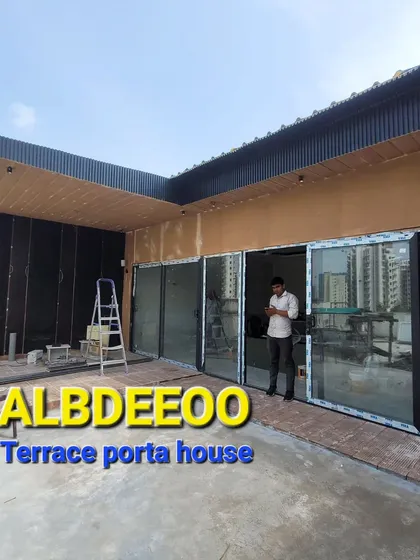 A nearly finished terrace porta house, showing the combination of wood-finish panels and large glass doors. The man in the photo gives a sense of the scale and spaciousness of the entrance.