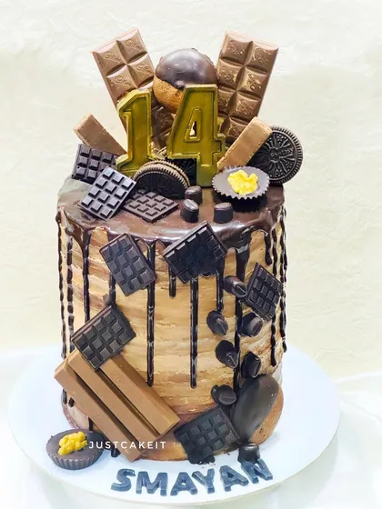 For the ultimate chocolate lover, I offer tall, decadent cakes like this Belgium chocolate creation. It's loaded with a variety of chocolate bars, cookies, and a rich drip for an unforgettable treat.