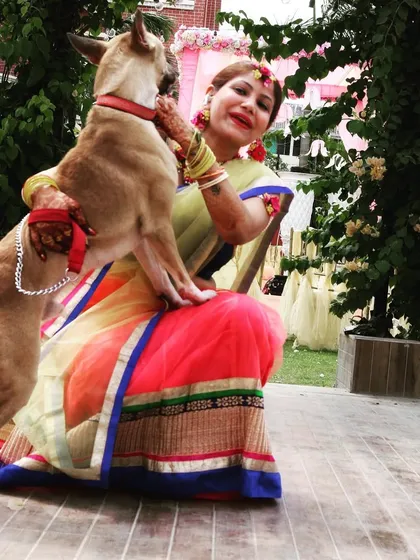A heartwarming photo from my Haldi ceremony, where I'm dressed in a colorful saree and floral jewelry, sharing a moment with my dog, Rocky.