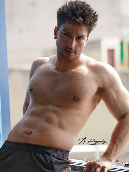 A classic fitness portrait showing off a well-defined torso. The natural lighting and relaxed pose create a confident and approachable look for a fitness professional.