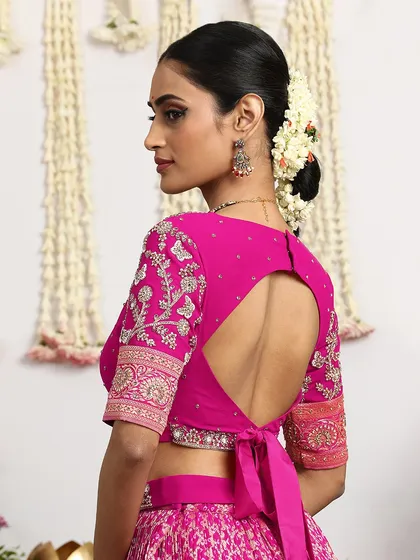 The back of this fuchsia blouse reveals a modern keyhole design with a delicate tie-up, blending contemporary style with traditional elegance. Every angle is designed to be a statement.