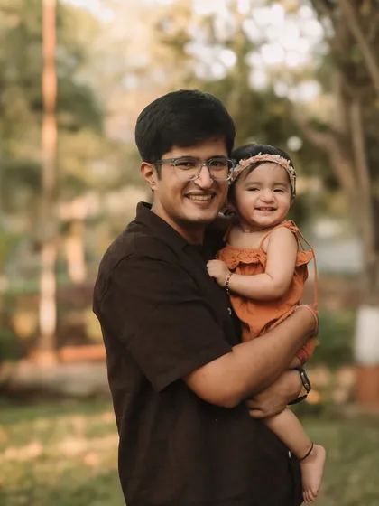 A proud dad holding his smiling daughter in the warm, golden light of an outdoor session.