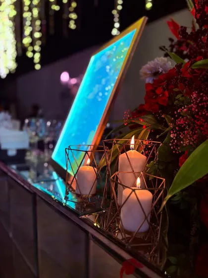 The warm glow of candles highlights a custom blue-lit menu, creating a beautiful contrast of colors on the mirrored bar top. Ambiance is key.