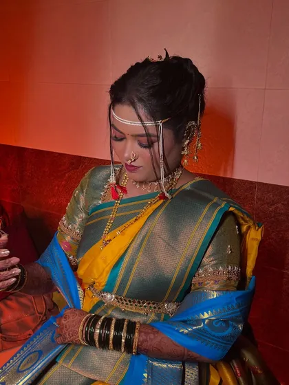 A quiet moment for the bride. The lighting highlights the texture of her saree and the smoothness of her makeup.