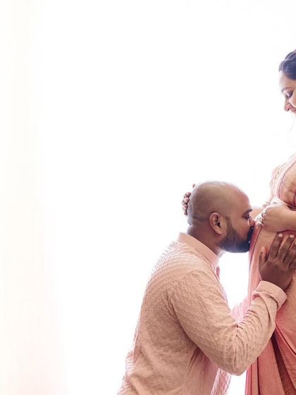 A gentle kiss for the baby. This high-key photograph is full of light and love, creating a timeless memory for the expecting parents.