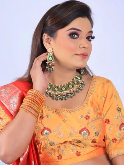A complete view of the party look with a yellow and red embroidered lehenga. The makeup is bright and festive, designed to complement the colorful traditional outfit.