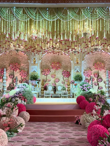 A symphony of blooms, brass, and carved elegance. This mandap, with its lotus-themed backdrop and floral-lined aisle, brings tradition and grandeur together in perfect harmony. 🌸