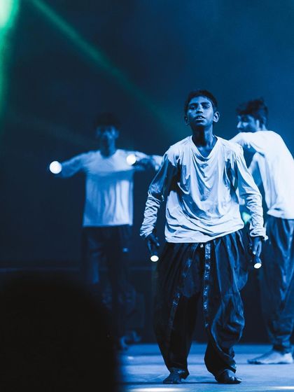 A young dancer looks up, caught in a cool blue light during a contemporary performance. My f/1.4 lens allows me to capture crisp details and mood even in the darkest stage environments.