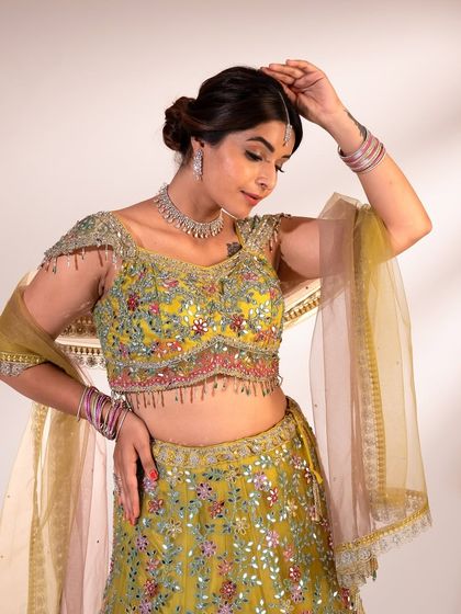 Another look at the stunning details of the green lehenga, focusing on the hand-embroidered blouse with delicate tassels and a matching maang tikka.