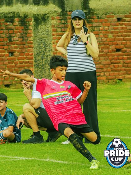 The passion of the game is captured as a player celebrates after taking a shot on goal, with his family watching proudly from the sidelines.