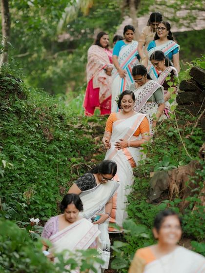 A candid shot of the bride and her friends descending a green, leafy staircase, all sharing a happy moment.