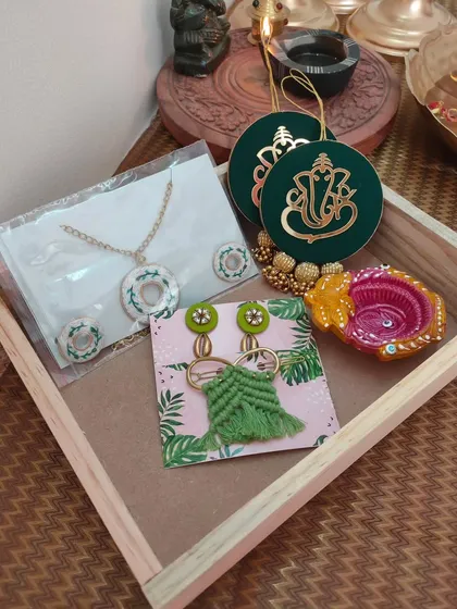 A mid-range Diwali hamper containing a Ganpati wall hanging, a necklace set, a decorative diya, earrings, and a hairpin. A perfect festive gift for friends and family.