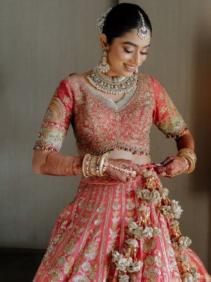 A final touch. The bride adjusts the tassels on her lehenga, a small detail that completes her breathtaking look.