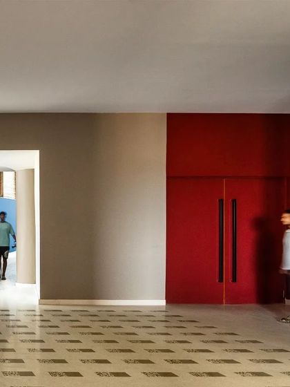 Spatial thresholds within the MARC Auditorium are defined by contrasting colors and textures. A bold red door marks a point of entry, while a blue curved wall invites movement, creating a dynamic and intuitive circulation path.