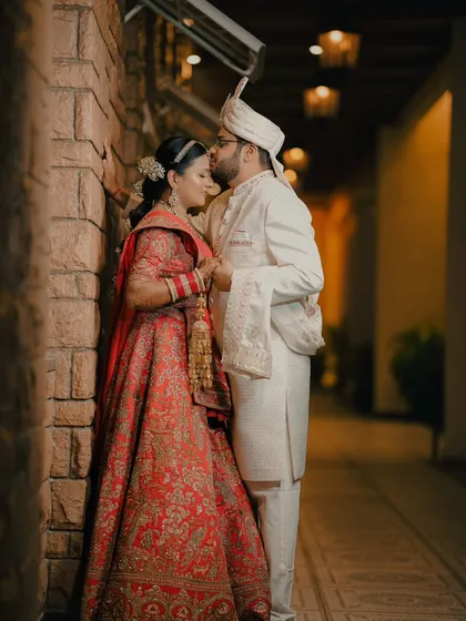 An intimate moment in a quiet corridor. The groom's gentle kiss on the bride's forehead is a timeless expression of love that we love to capture.