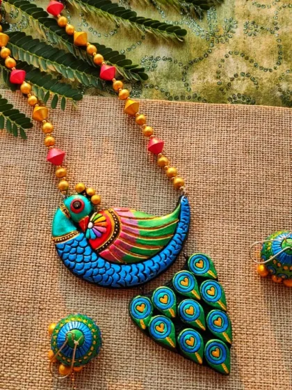 This artistic peacock necklace is one of my signature creations, a piece I am incredibly proud of. I meticulously sculpt and paint each feather detail with metallic hues to create a vibrant, textured look. The set includes matching jhumka earrings, making it a complete statement piece for any celebration.