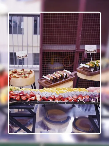 A wide shot of a modern buffet spread featuring a variety of appetizers. You can see fruit skewers, tacos, and mini pizzas, demonstrating the breadth of my menu offerings.