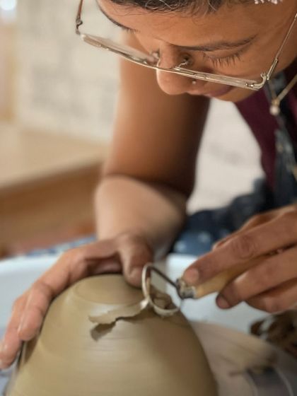 A close up of the trimming process, a quiet, focused moment that is a crucial part of the pottery journey.