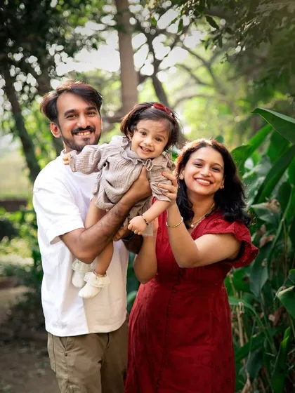 A joyful family portrait in the park. Lifting their daughter up brings out genuine laughter and creates a dynamic, love-filled image.
