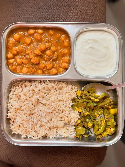 A balanced meal of brown rice, channa masala, sautéed ivy gourd, and curd. This is a classic Indian meal that is both delicious and nutritious.
