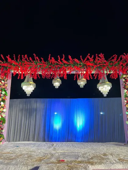 A close-up of the red floral header and chandeliers from the previous stage design. This highlights the contrast between the vibrant flowers and the sparkling crystals.