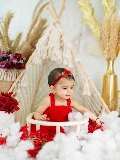 A candid moment of a little girl in a red dress playing in a sea of cotton clouds, set against a boho teepee.