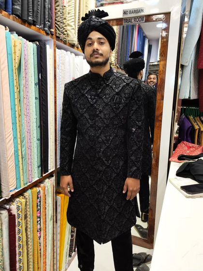 A groom looking sharp in a black self-embroidered sherwani and a matching black turban. The handwork adds texture and depth, making it a sophisticated choice for an evening reception.