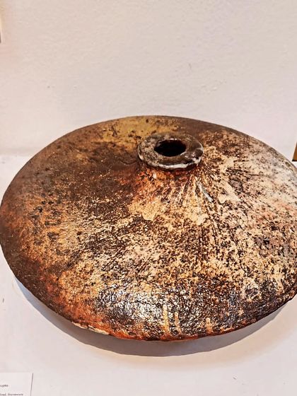 This wood-fired ceramic piece has a unique, rustic texture and coloration that can only be achieved through that specific firing process. It stands as a beautiful, one-of-a-kind decorative object.