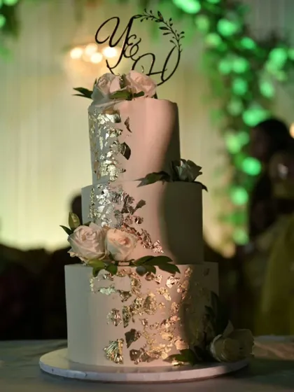 The white and gold leaf wedding cake captured at the event, with beautiful soft lighting.