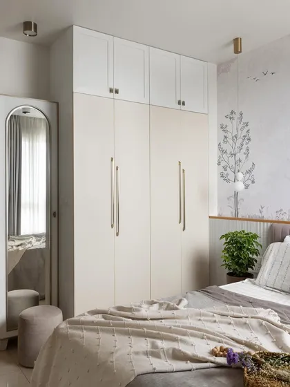 This guest bedroom exudes timeless elegance with classic white and gold accents. A dual-tone wardrobe provides ample storage, while a full-length arched mirror adds a touch of sophistication.